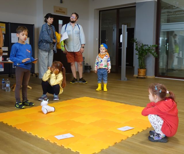 część uczestników gra sterują robotami przy użyciu tabletów, pozostali stoją i patrzą