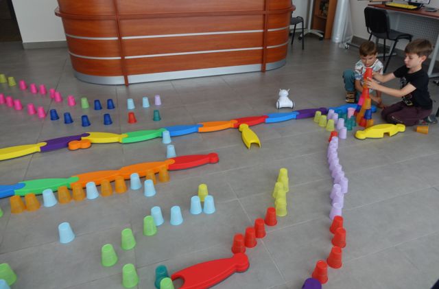 kolorowe kubeczki ułożone na podłodze w taki sposób że tworzą tor przeszkód dla robotó photon, dzieci sterują robotami używając tabletów
