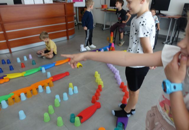 kolorowe kubeczki ułożone na podłodze w taki sposób że tworzą tor przeszkód dla robotó photon, dzieci sterują robotami używając tabletów