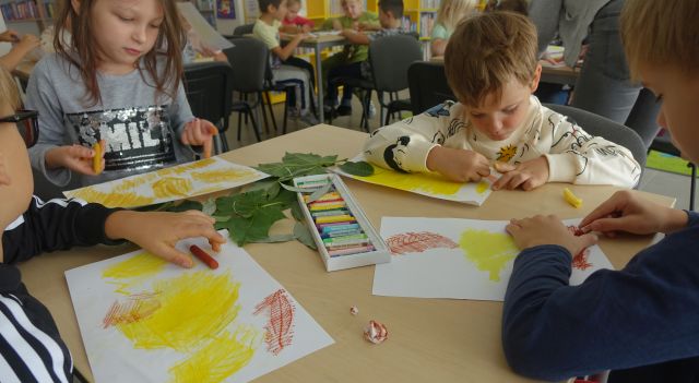 dzieci przy stolikach malują kredkami