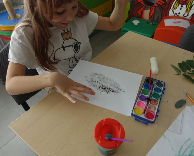 dziewczynka zachwycona narysowanym przez siebie liściem