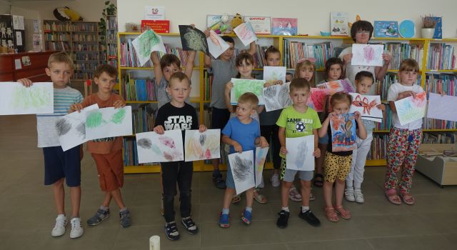 dzieci pozują do zdjęcia z wykonanymi przez siebie ilustracjami liści