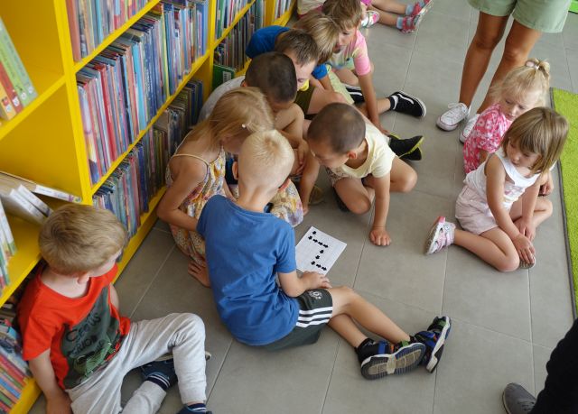 przedszkolaki siedzą na podłodze i rozwiążują zadanie