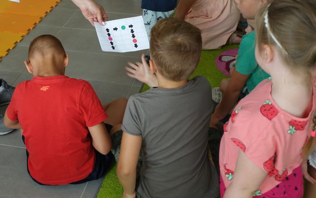 przedszkoalki siedzą na podłodze i rozwiązują zadanie