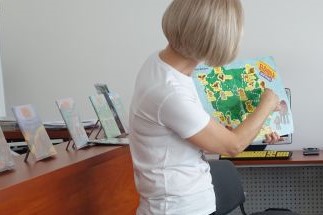bibliotekarka pokazuje książkę z mapą polski