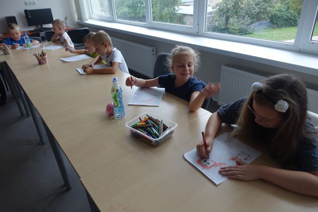 dzieci przy stolikach rozmkodowują obrazki