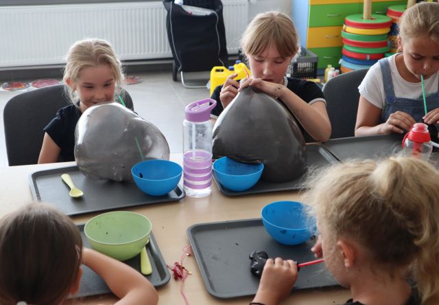 dzieci dmuchają przez plastikowe rurki w slimy, powstają ogromne kule