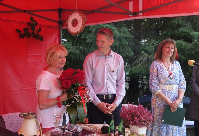 stoi dyrektorka biblioteki, mężczyzna oraz aktorka z kwiatami