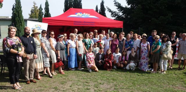 uczestnicy Narodowego Czytania pozują do zdjęcia na tle namiotu z logo biblioteki