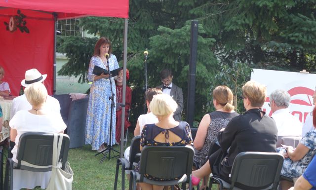 dyrektorka biblioteki ubrana w błękitną sukienkę wita zgromadzonych gości