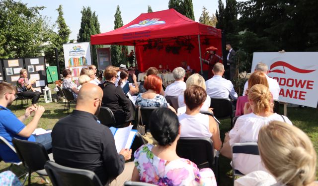 zdjęcie publicznośći na Narodowym Czytaniu zrobione od tyłu, przed nimi czerwony namiot