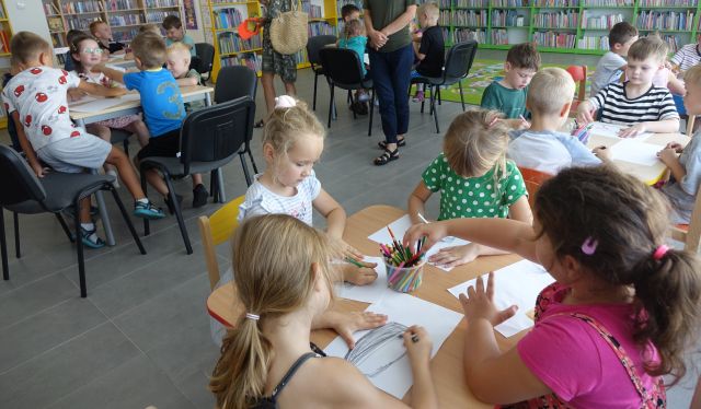 przedszkolaki przy stolikach wykonują ilestracje
