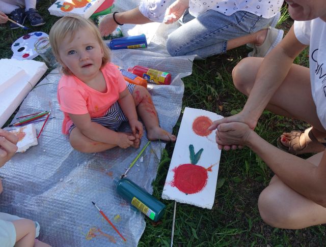 małą dziewczynka siedzi na folii, przed nią rysunek kwiatów