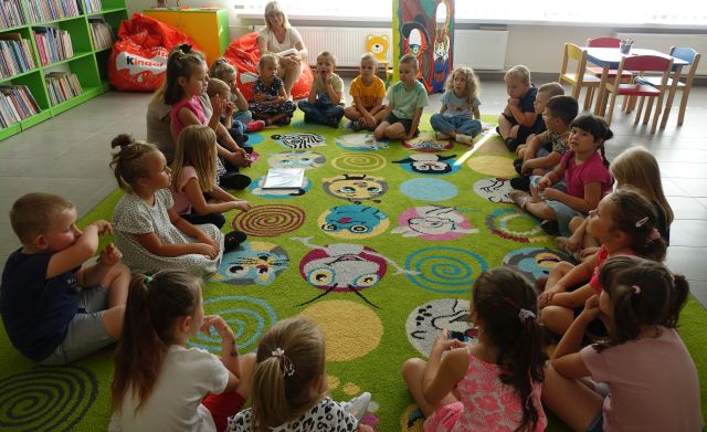 dzieci siedzą na kolorowym dywanie