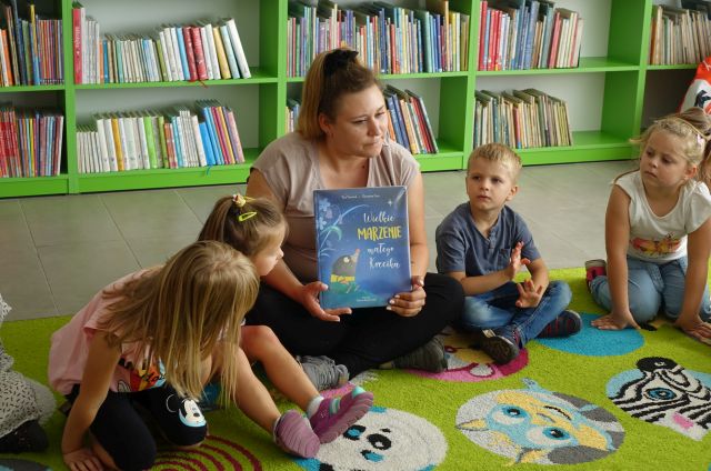 bibliotekarka pokazuje dzieciom książkę