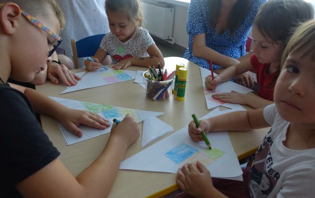 dzieci malują na kartkach siedząc przy stolikach