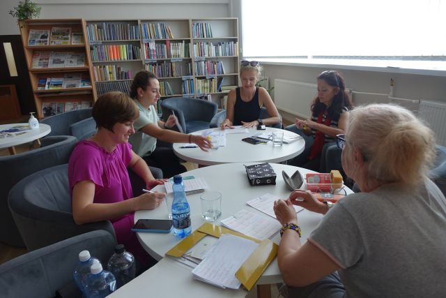 uczestniczki siedzą przy okrągłych stołach i uczą się