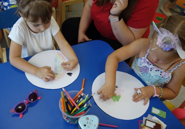 dzieci siedzą przy stoliku i malują na kołąch wyciętych z kartek