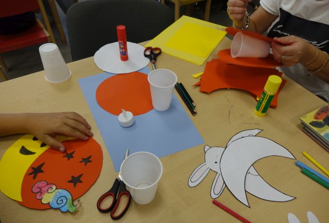 dzieci wycinają z kartek kolorowe lampiony