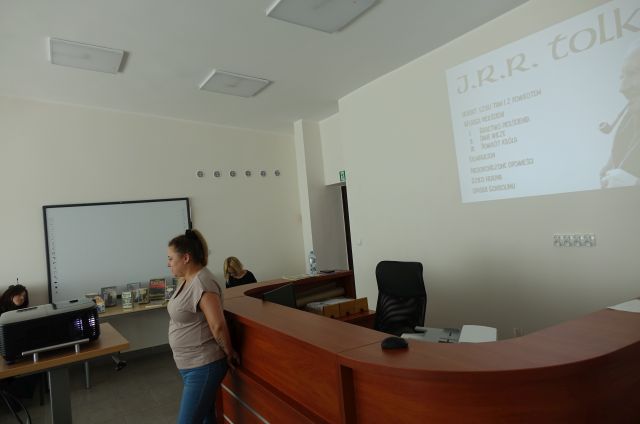 bibliotekarka stoi przed siedzącą młodzieżą i opowiada