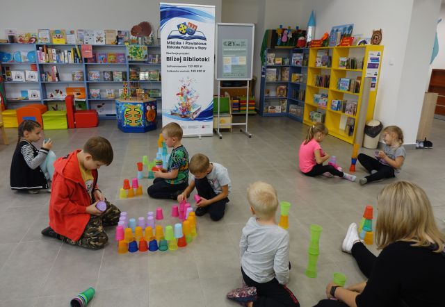 dzieci układają na podłodze wieże z kolorowych kubeczków