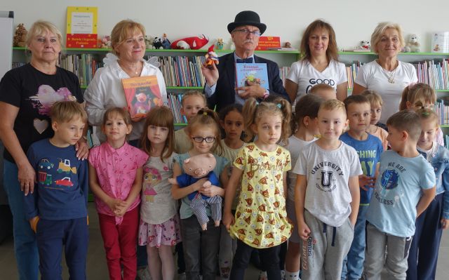 przedszkolaki i nauczycielki pozują do zdjęcia z pisarzem