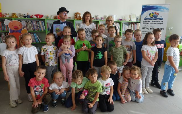 przedszkolaki i nauczycielki pozują do zdjęcia z pisarzem