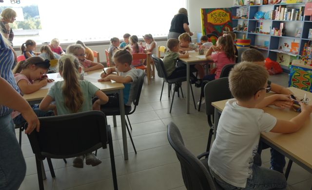 przedszkoalki siedzą przy stołach i malują