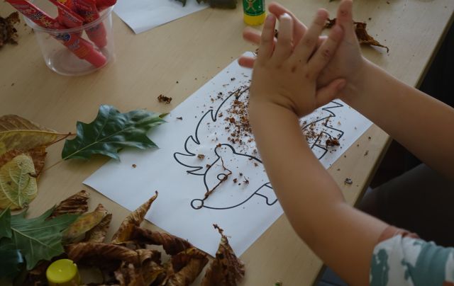 chłopiec rozciera w dłoniach liście i kruszy na kartkę