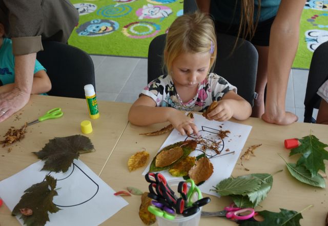 dziewczynka wykleja z liści liście w wazonie