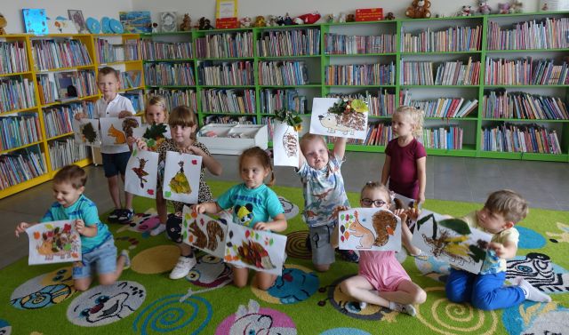 dzieci pozują do zdjęcia z wykonanymi przez siebie kompozycjami z liści