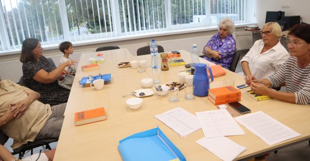 uczestnicy Dyskusyjnego Klubu Książki siedzą przy stołach