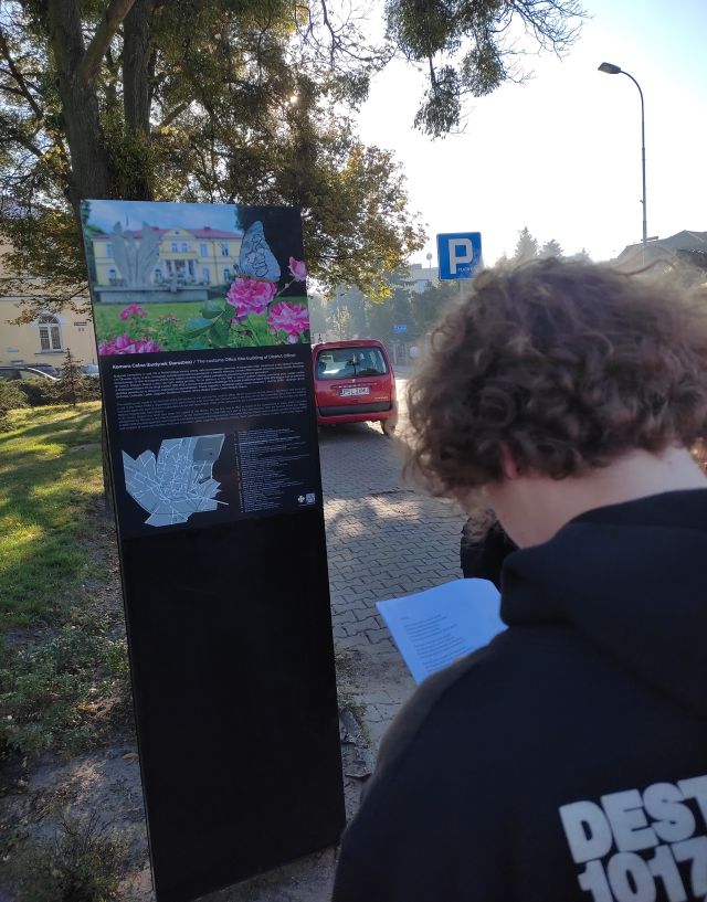 młodzież czyta infomracje na tablicy w przestrzeni miejskiej