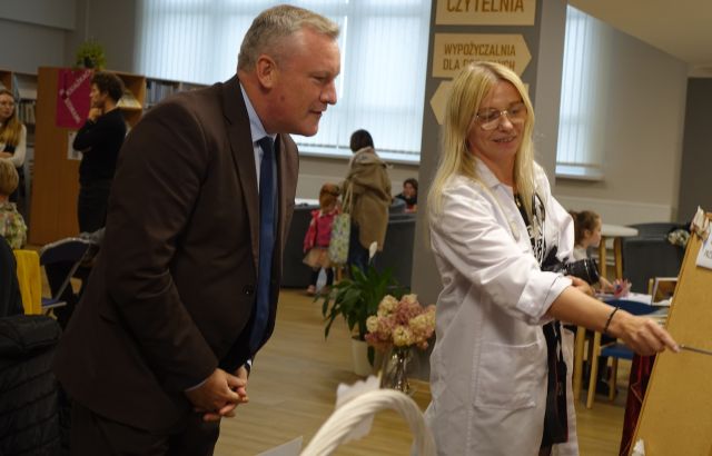 kobieta w fartuchu pielęgniarskim sprawdza wzrok mężczyźnie w brązowym garniturze
