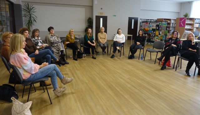 15 kobiet siedzi w okręgu na krzesłąch