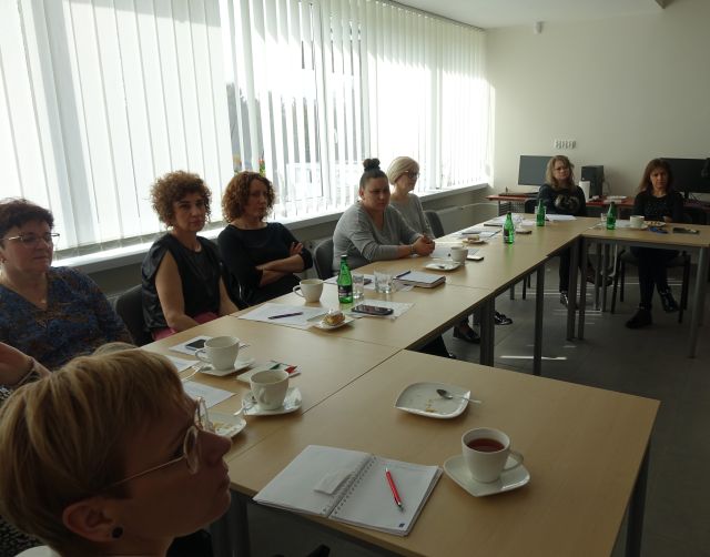 osoby dorosłe siedzą przy stołąch, na których leżą kartki i filiżanki, sala komputerowa