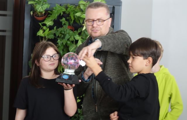 chłopiec i dziewczynka przy pomocy pisarza produkują prąd przy użyciu kuli