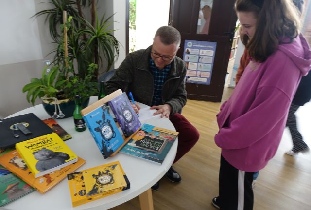 pisarz podpisuje dziewczynce książkę