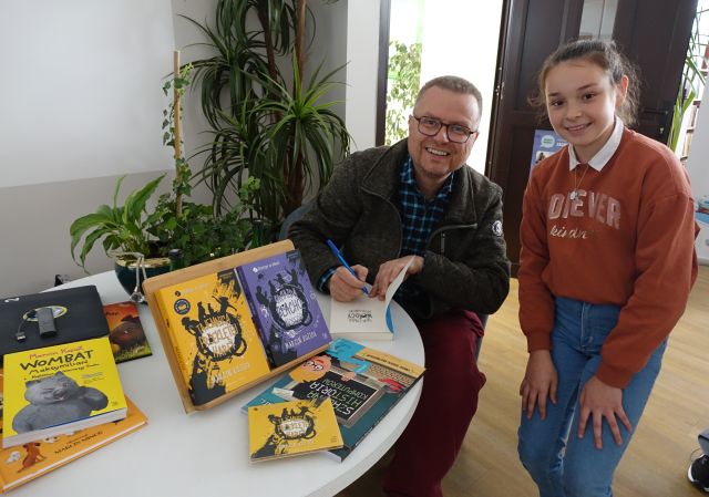pisarz podpisuje dziewczynce książkę