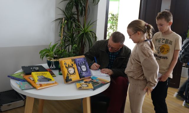 pisarz podpisuje się młodzieży na kartkach