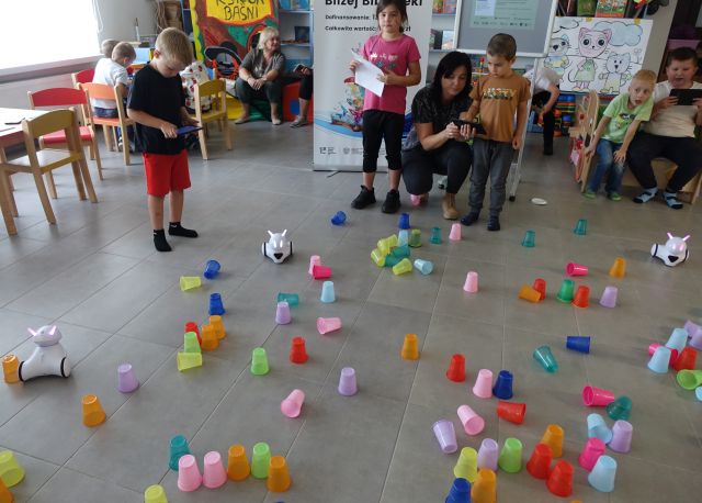 dzieci sterują robotami Photon, które jeżdżą pomiędzy kolorowymi kubeczkami