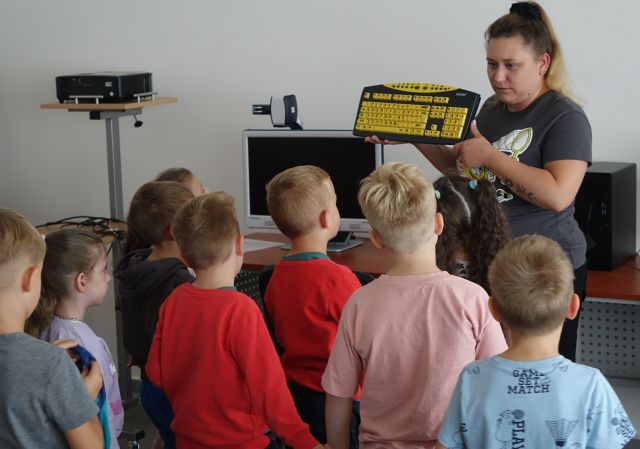 przedszkoalki patrzą na pokazywaną przez bibliotekarkę klawiaturę dla niedowidząccych