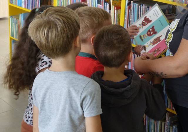 dzieci oglądają pokazywaną przez bibliotekarkę książkę