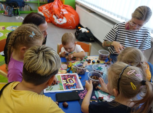 dzieci i mamusie lepią ludziki z plasteliny, kasztanów i żołędzi