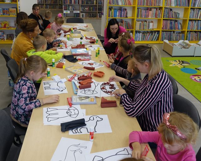 dzieci i opiekunowie wyklejają z kulek z bibuły psy