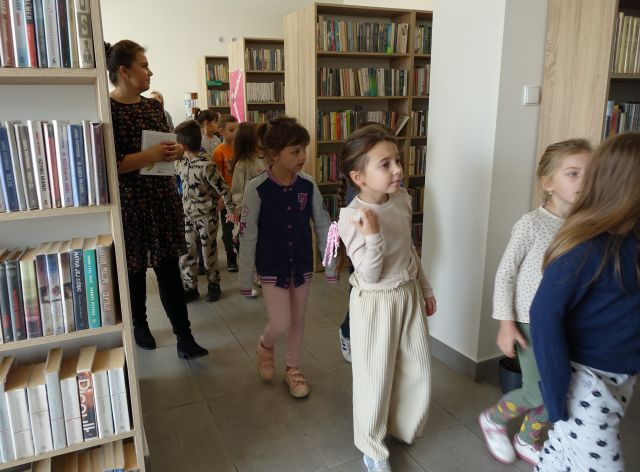 przedszkolaki maszerują między regałami z książkami