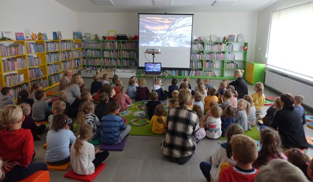 przedszkolaki i opiekunowie siedzą i oglądają bajkę