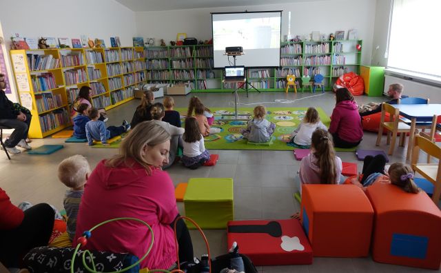 dzieci z opiekunami oglądają bajkę wyświetlaną z rzutnika na ekran