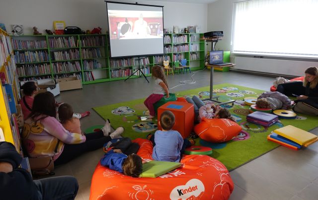 dzieci z opiekunami oglądają bajkę wyświetlaną z rzutnika na ekran