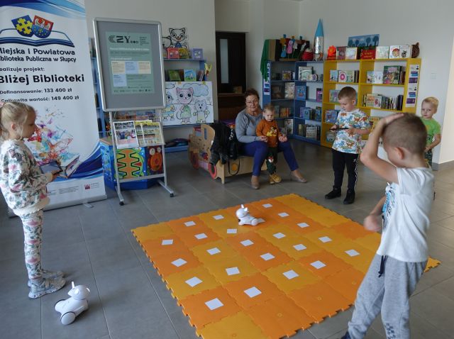 dzieci sterują przy użyciu tabletów robotami Photon jeżdżącymi po pomarańczowej macie